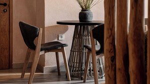 Een moderne eethoek met een ronde tafel, twee stoelen, een potplant en hangende吊灯.