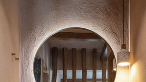 Een badkamer met een ronde spiegel, houten balken, een wastafel en een wandlamp.