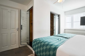 Un dormitorio con una cama, una puerta, un ventanal corredero y una ventana.
