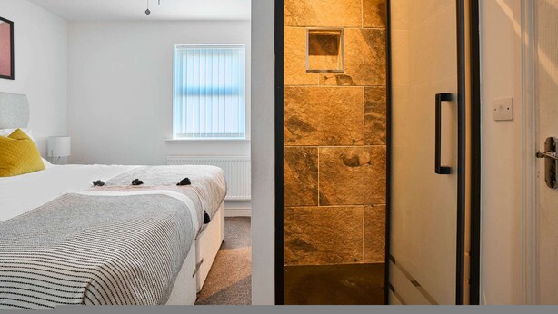 Un dormitorio con cama, una ventana con persianas, un ventilador de techo y una mesita de noche con lámpara.