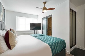 Une chambre à coucher avec un lit, un ventilateur de plafond, une télévision et une porte coulissante.