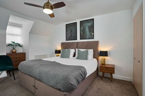 A bedroom with a bed, bedside tables, a ceiling fan, a plant, and framed artwork on the wall. - Host Stay Snowdrop Crescent I (Launceston)