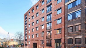Ein mehrgeschossiges Backsteingebäude mit modernem Design, große Fenster und ein Flachdach.