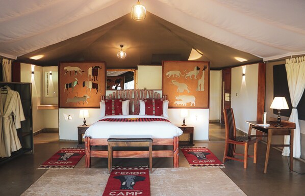A spacious bedroom with a large bed, a wooden chair, a desk, and a mirror.