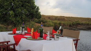 A table set outdoors with a view of a river and grassy hills. - Tembo By Jackson  (Maasai Mara)