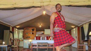A room with a bed, a chair, a table, and a hanging light fixture. - Tembo By Jackson  (Maasai Mara)