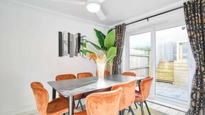 Un comedor con una mesa y sillas, un ventilador de techo y un ventanal corredero que da a un espacio exterior.