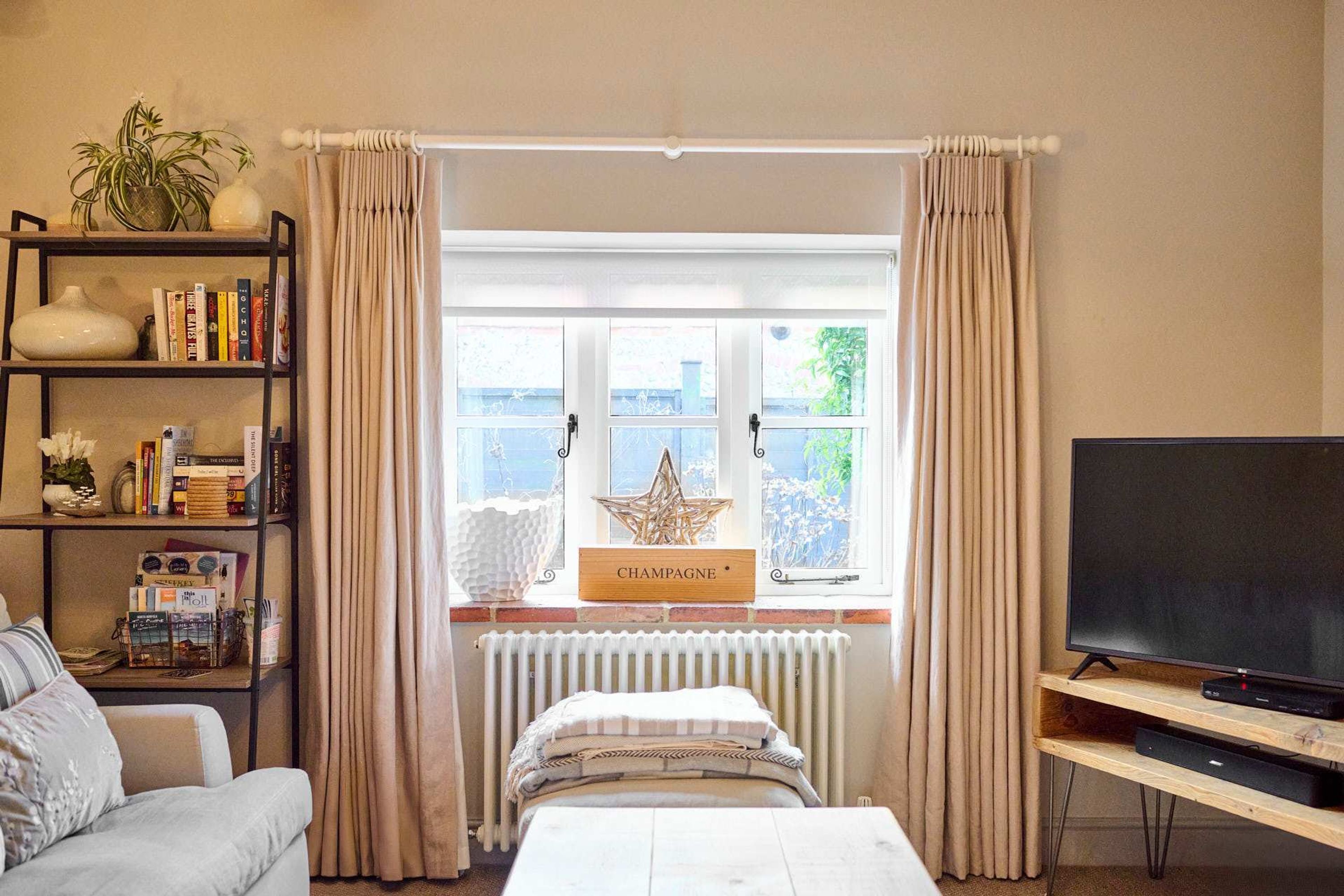 A bedroom with a bed, a bookshelf, a television, and a window with curtains.