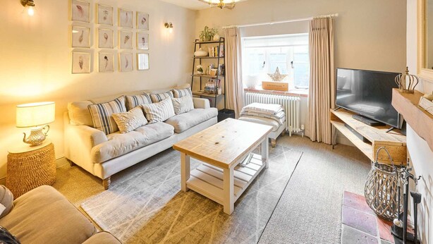 A cozy living room with a sofa, coffee table, and TV. - Host Stay Rock Rose (Holt)
