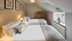 A bedroom with two beds, a wooden wardrobe, a radiator, and framed artwork on the wall. - Host Stay Rock Rose (Holt)