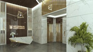 A modern reception area with a marble reception desk, wooden accents, and a potted plant. - Studio with Canal Views by Bespoke  (Dubai)