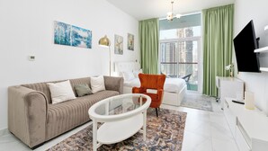 A modern living room with a sofa, armchair, and a glass coffee table. - Studio with Canal Views by Bespoke  (Dubai)