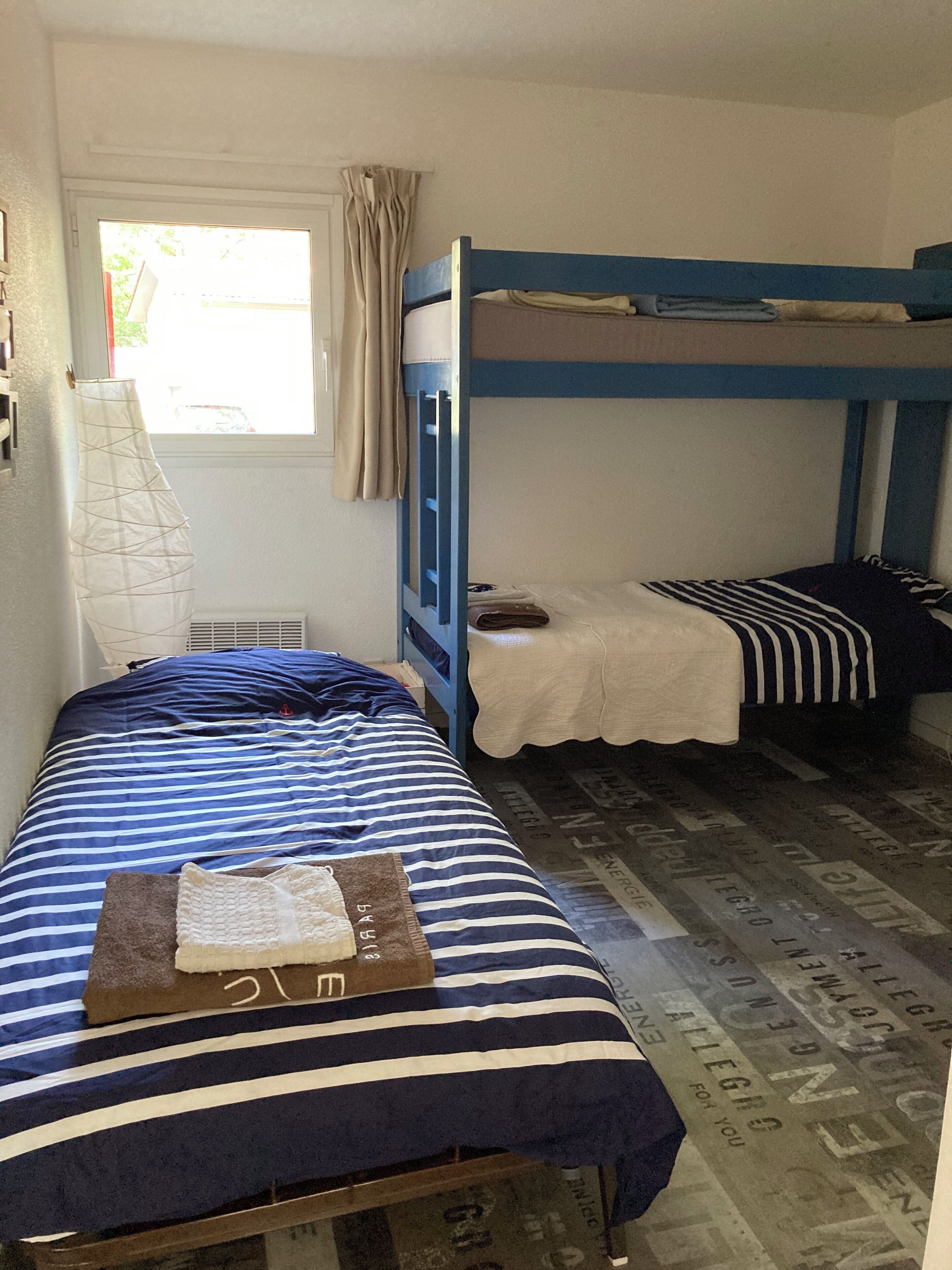 A dormitory room with two bunk beds, a window with curtains, and a radiator.