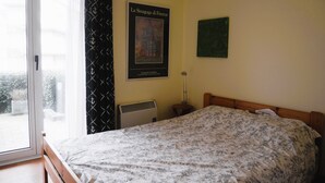 Une chambre à coucher avec un lit, un radiateur, une fenêtre avec des rideaux et une affiche accrochée au mur.