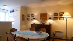 Un coin repas avec une table ronde, des chaises en osier, une nappe blanche et un set de table bleu.