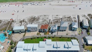 Eine Vogelperspektive auf einen Küstenort mit mehreren Gebäuden, einem Swimmingpool und einem Sandstrand.