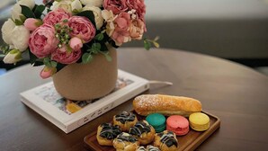 A bouquet of flowers on a table with pastries and a book.