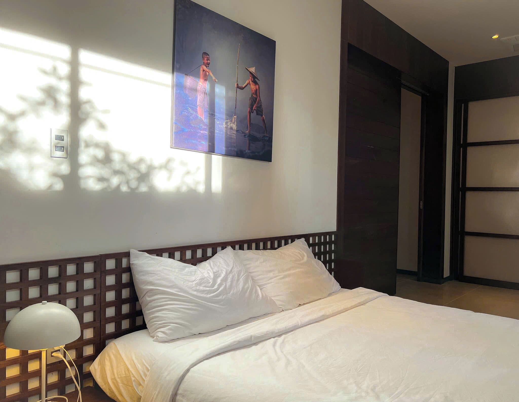 A neatly made bed with white linens in a modern hotel room.