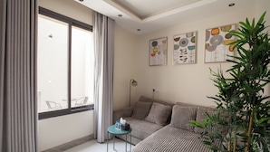 Une chambre à coucher moderne avec une grande fenêtre, un canapé, une petite table et une plante en pot.