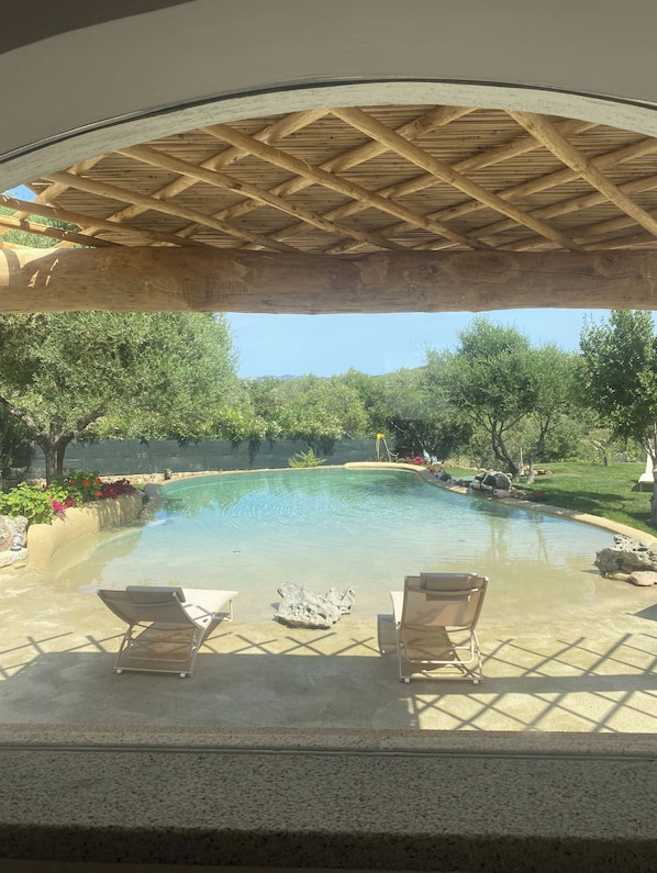 Una piscina al aire libre, sillones reclinables de piscina