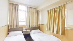 A hotel room with two single beds, a bedside table with a lamp, and curtains on the windows. - Nanqiang Hostel (Kowloon)