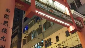 A multi-story building with a prominent red and white entrance archway. - Nanqiang Hostel (Kowloon)