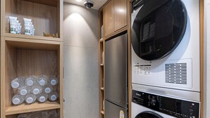 A compact laundry area with a front-loading washer and dryer, wooden shelving with glass bottles, and a stainless steel refrigerator. - Bread Hill Hotel Jongno (Seoul)