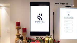 Ein Self-Check-in-Terminal mit einem Bildschirm, der das Logo des Bread Hill Hotel & Suites sowie ein Sprachauswahlmenü anzeigt.