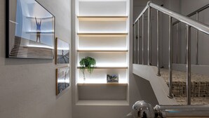 Eine moderne Treppe mit Metallgeländern und einem kleinen Fenster mit Regalen.