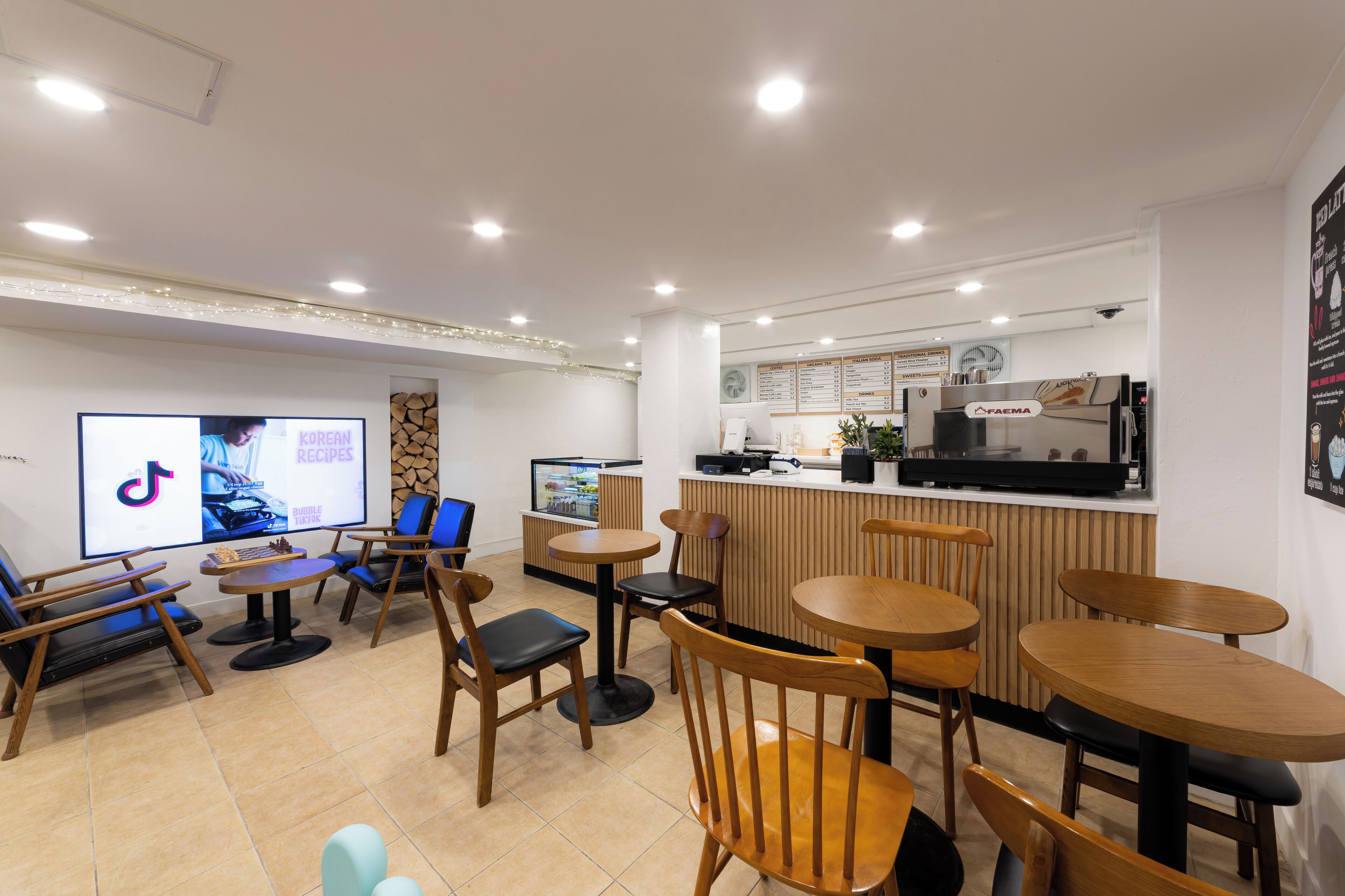A modern cafe with wooden furniture, a digital menu board, and a coffee machine.