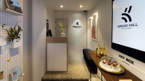 A modern hotel reception area with a reception desk, a key box, and a buffet table with food and drinks. - Bread Hill Hotel Jongno (Seoul)