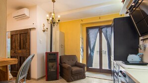Una cocina compacta con zona de comedor, un sillón marrón y una puerta de madera.