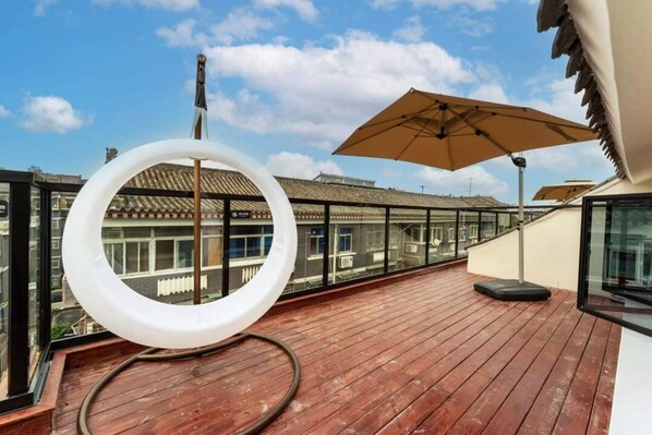 A wooden deck with a glass balustrade, a white circular object, and a beige umbrella. - Shi San Du Fu Qing Nian Lv She (Xi'an)