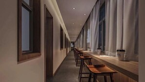 Un largo pasillo con taburetes de madera y una barra, probablemente un café o zona de descanso en un hotel.