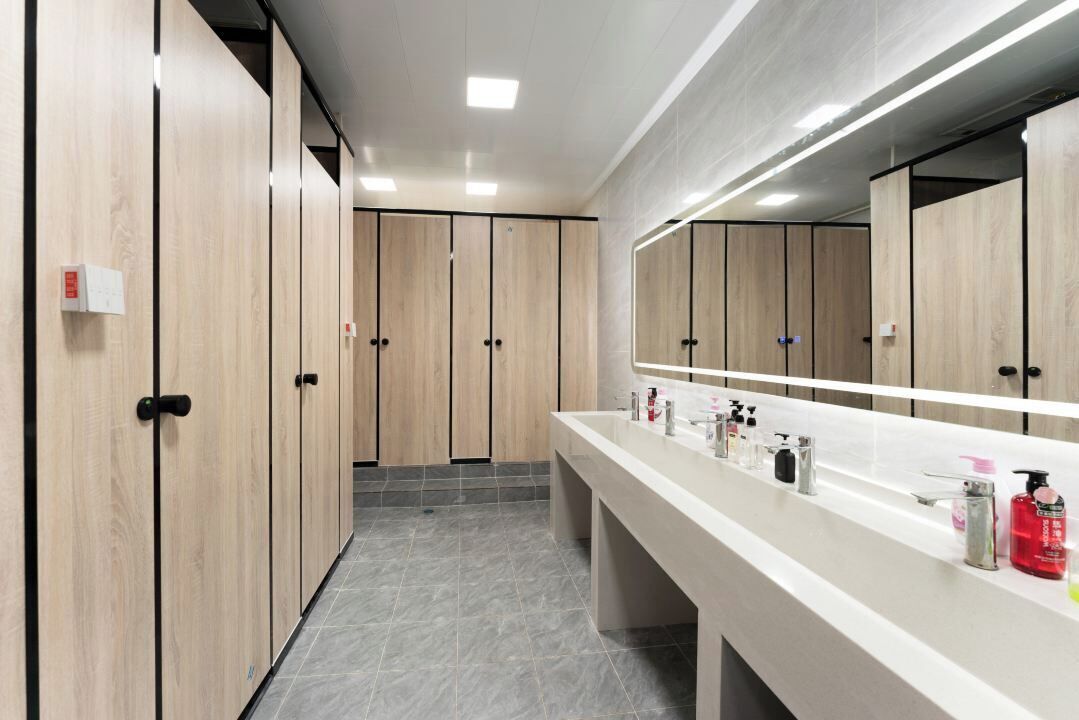 A modern bathroom with wooden lockers, a long vanity with multiple sinks, and a large mirror.
