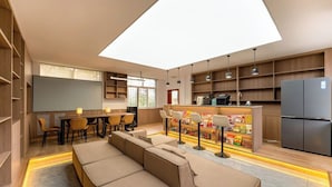 Una sala moderna con un juego de sofá, un comedor y una cocina con refrigerador y estanterías.