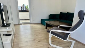 Een moderne woonkamer met een bank, een televisie en een fauteuil.
