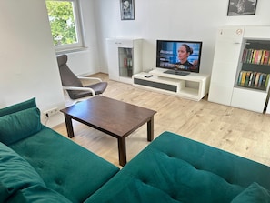 A living room with a TV, sofa, and bookshelf.