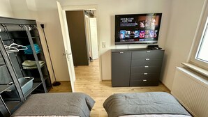 Een slaapkamer met twee bedden, een kledingkast, een televisie en een radiator.