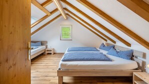 Slaapkamer in een loftstijl met een houten plafond, een bed met geruit beddengoed, een klein nachtkastje en een lijst met een afbeelding aan de muur.
