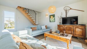 Un salon moderne avec un escalier, un ensemble de canapés, une table basse et un téléviseur.