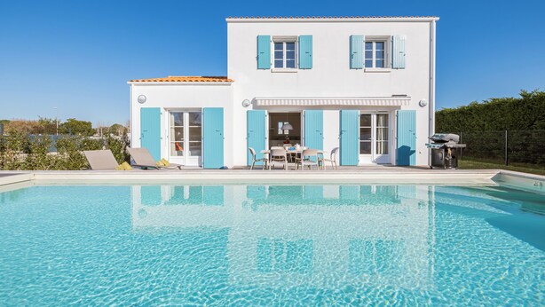 Une maison à deux étages avec une piscine à l’avant.
