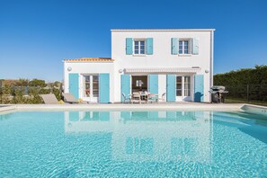 Ein zweistöckiges Haus mit Schwimmbecken davor.