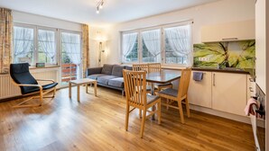 A modern living room with a sofa, chairs, a dining table, and large windows. - Holiday Apartment 'Waldblick' with Shared Pool and Large Terrace (Wolfach-Kirnbach)