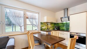 A compact kitchen with a dining area, a built-in stove, and a window with sheer curtains. - Holiday Apartment 'Waldblick' with Shared Pool and Large Terrace (Wolfach-Kirnbach)