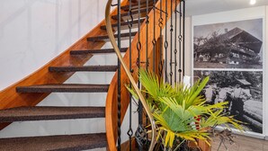 A wooden spiral staircase with metal railings, a woven carpet, and a potted plant. - Holiday Apartment 'Hofblick' with Shared Pool (Wolfach-Kirnbach)