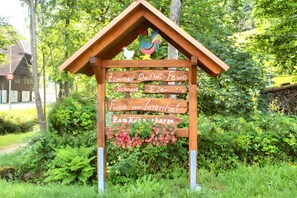 A wooden sign with directional arrows and text, surrounded by greenery.