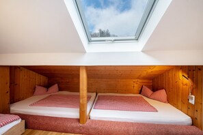 A room with two beds, a skylight, wooden walls, and a red carpet. - Holiday Apartment 'Bergblick' with Balcony (Wolfach-Kirnbach)