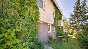 A house with a garden, a patio with chairs, and a small table. - Apartment 'Kaltenbach' with Shared Terrace, Shared Garden and Wi-Fi (Schonach)