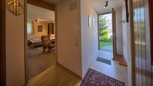 A hallway leading to a bedroom with a bed, a chair, and a small table. There is a door with a mirror and a light fixture on the ceiling. - Apartment 'Kaltenbach' with Shared Terrace, Shared Garden and Wi-Fi (Schonach)